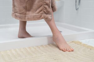 Woman stepping out of a Safe Step walk-in shower with EZ Step base